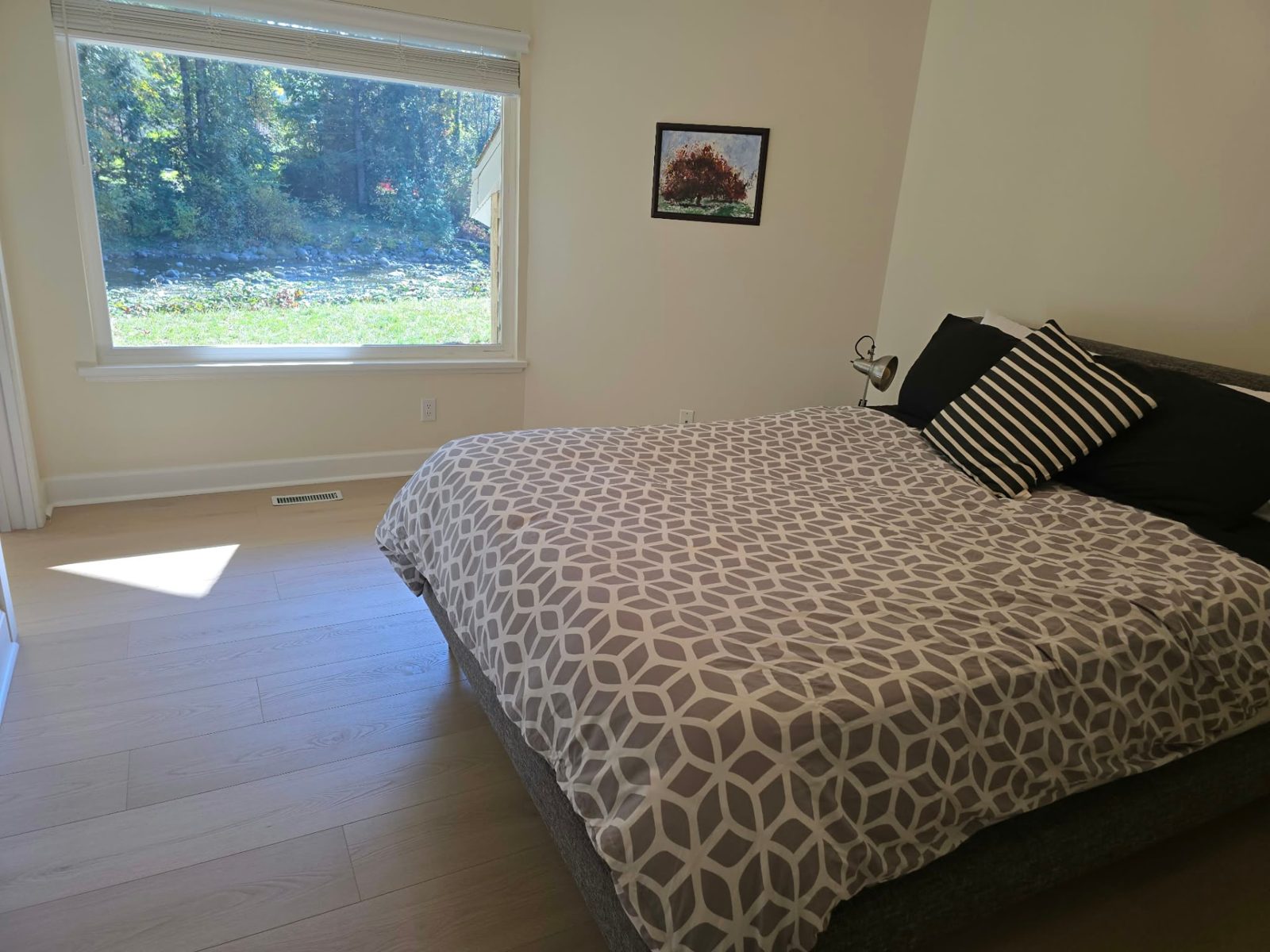 Primary bedroom with a picture window looking onto the lawn and the Seymour River.