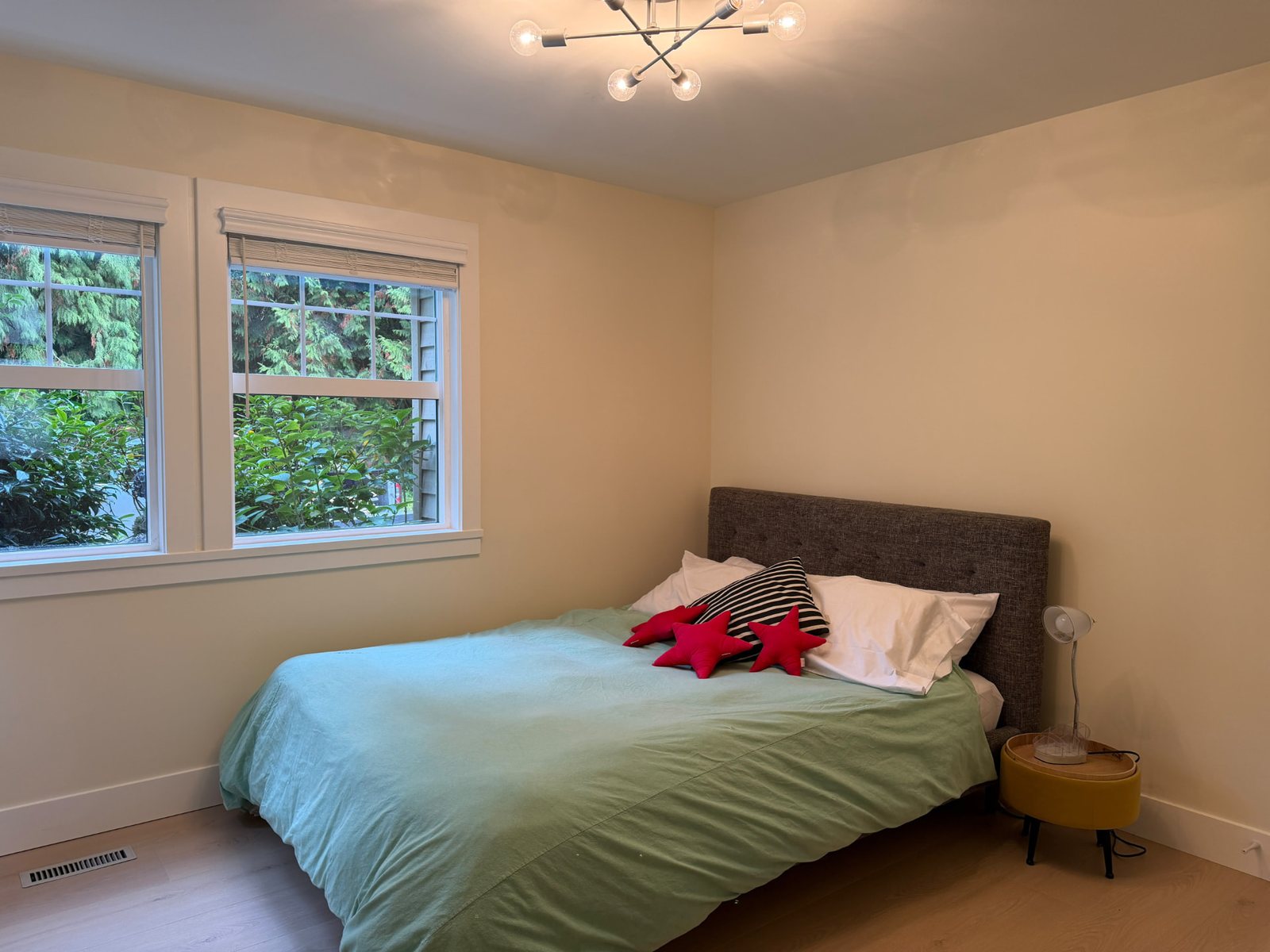 Second bedroom with a green duvet and two windows onto the garden.