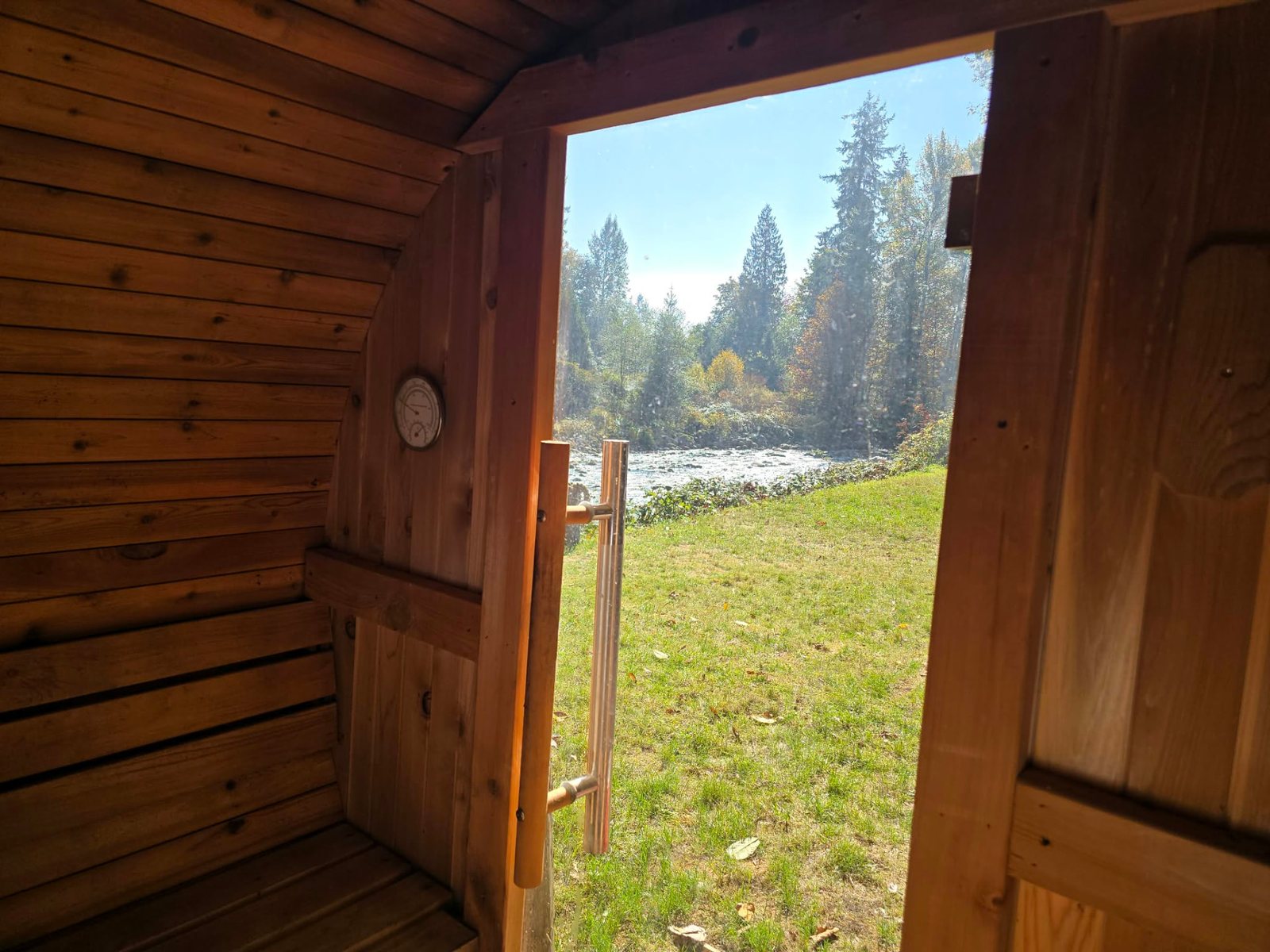 View from inside the barrel sauna through its open door to the lawn and the Seymour River.